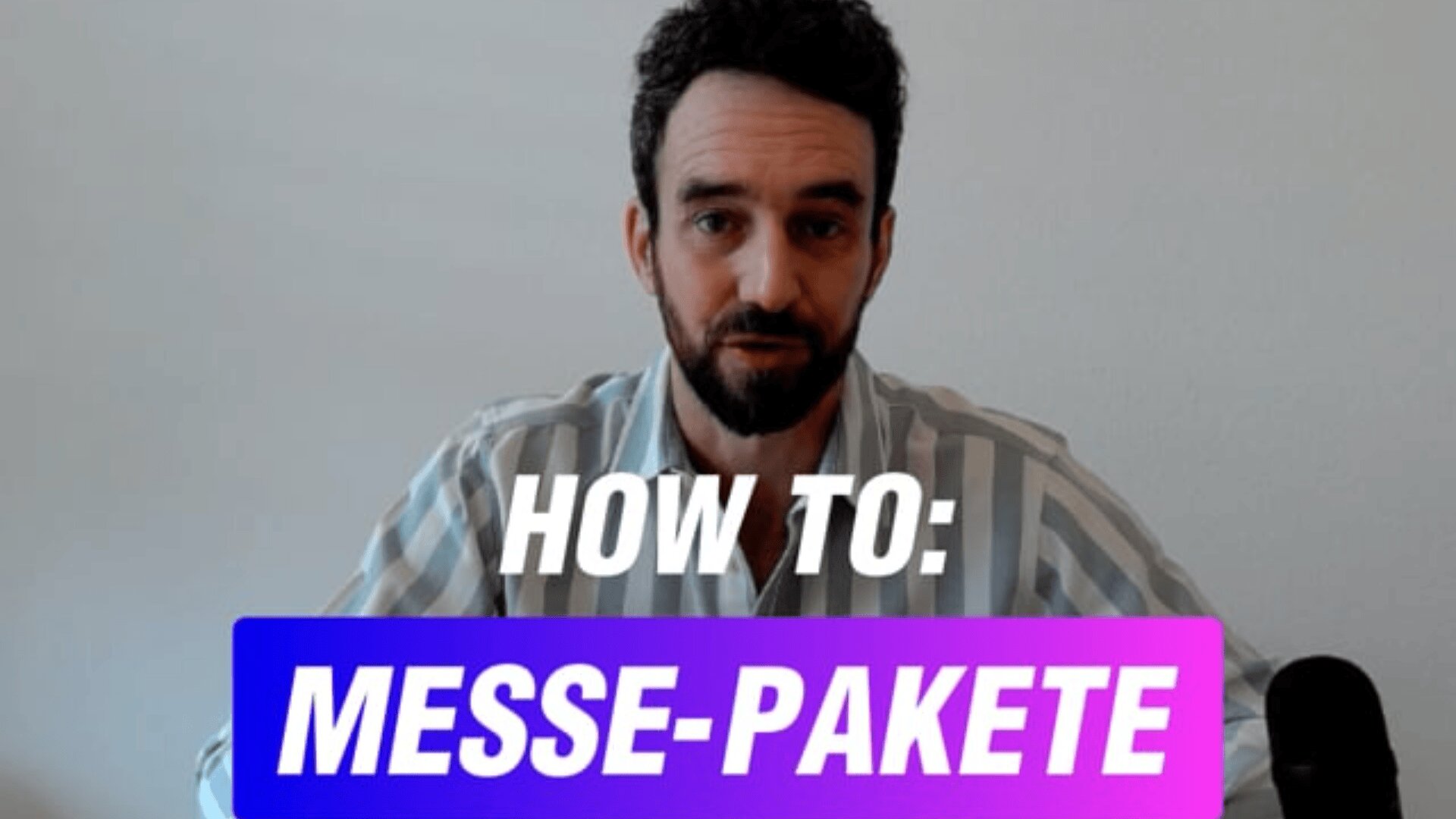 Ein Mann mit kurzen dunklen Haaren und Bart sitzt an einem Tisch vor einer weißen Wand. Der eingeblendete Text lautet „HOW TO: MESSE-PAKETE“ in weiß-violetter Farbverlaufsschrift. Rechts ist ein Mikrofon zu sehen.