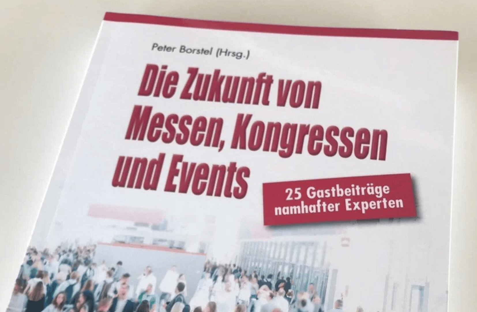 Book cover titled Die Zukunft von Messen, Kongressen und Events with a subtitle about 25 expert contributions. The background shows a blurred crowd of people at an event or conference.